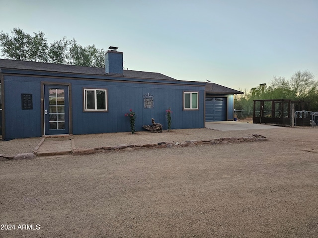 back house at dusk featuring a garage