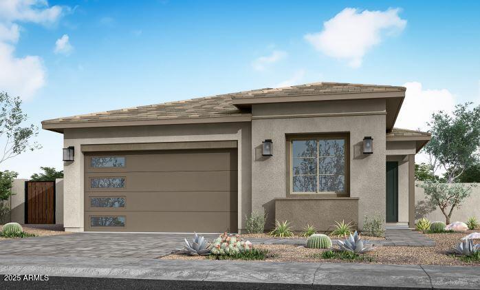 prairie-style house featuring stucco siding, decorative driveway, a garage, and fence