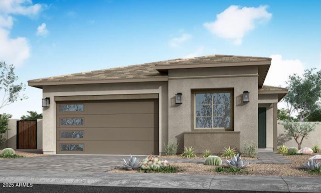 prairie-style house featuring stucco siding, decorative driveway, a garage, and fence