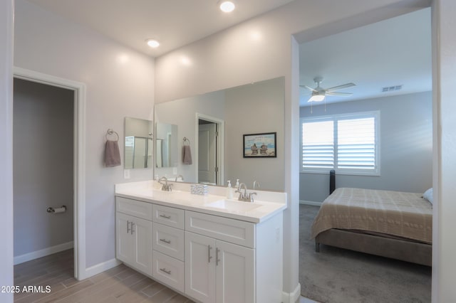 ensuite bathroom with visible vents, a sink, double vanity, baseboards, and ceiling fan