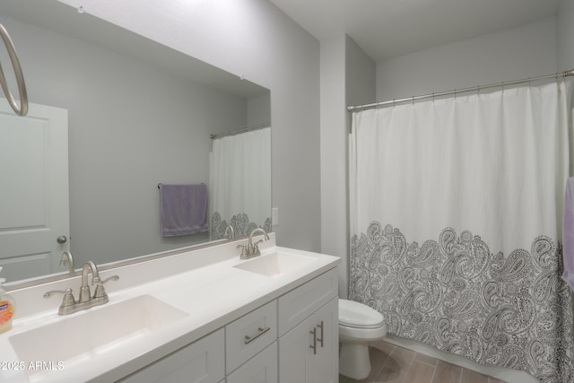 bathroom featuring a sink, toilet, wood finished floors, and double vanity