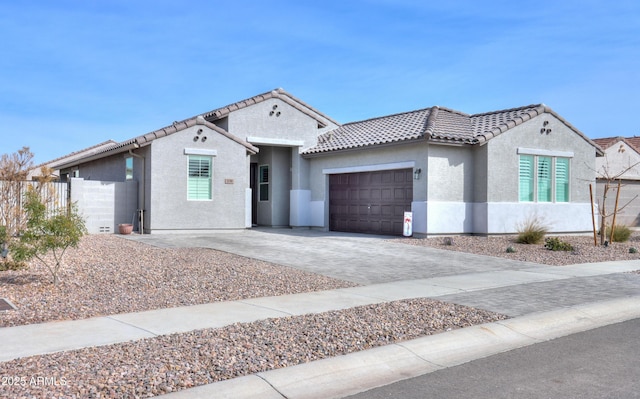 view of front of property with a tiled roof, an attached garage, driveway, and stucco siding