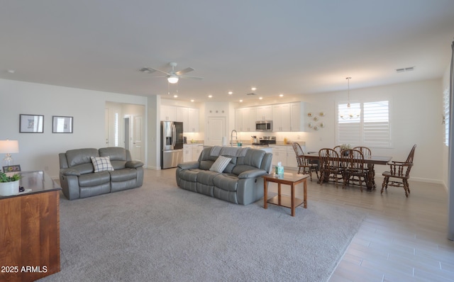 living area featuring visible vents, baseboards, and a ceiling fan