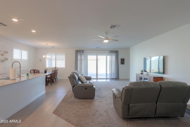 living room featuring sink, ceiling fan with notable chandelier, and light wood-type flooring