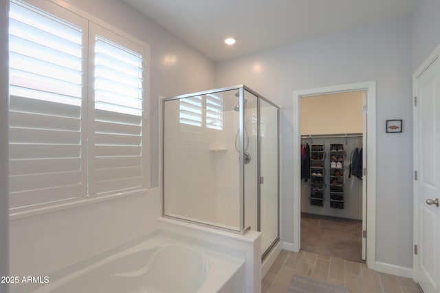 full bath featuring baseboards, recessed lighting, a stall shower, a spacious closet, and a bath