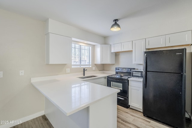 kitchen with kitchen peninsula, black appliances, light wood-type flooring, white cabinetry, and sink