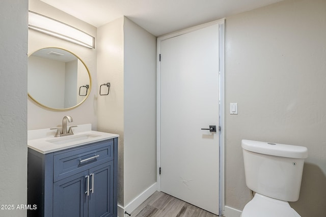 bathroom featuring toilet, vanity, and hardwood / wood-style floors