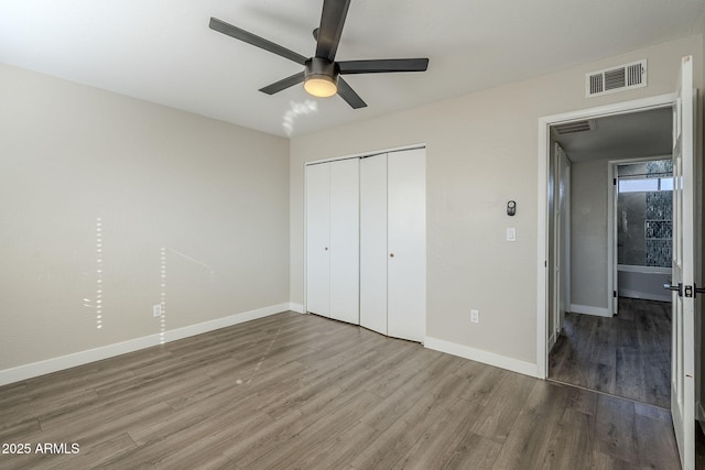 unfurnished bedroom with ceiling fan, a closet, and hardwood / wood-style floors