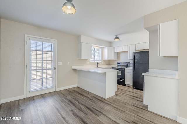 kitchen with black appliances, light wood-type flooring, kitchen peninsula, sink, and white cabinetry