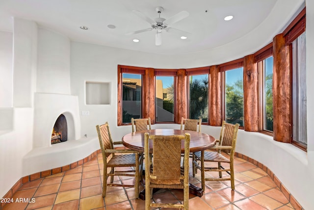 tiled dining space with ceiling fan and a fireplace