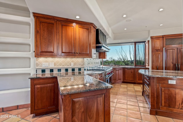 kitchen with high quality appliances, light tile floors, a center island, wall chimney range hood, and backsplash