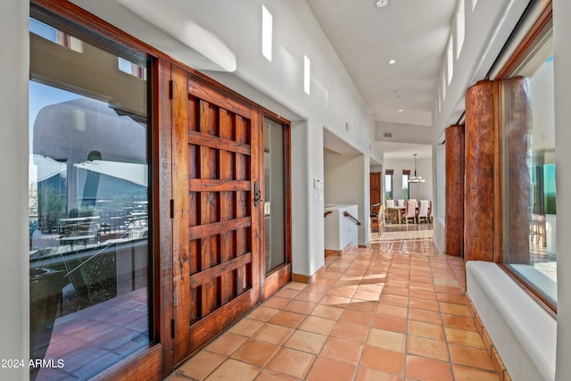 corridor with light tile flooring and a chandelier