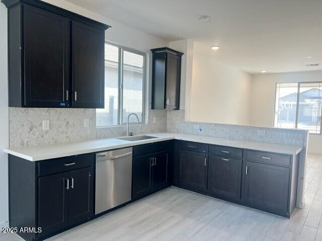 kitchen with sink, stainless steel dishwasher, kitchen peninsula, light hardwood / wood-style floors, and decorative backsplash