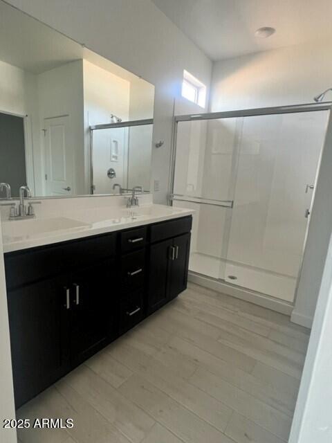 bathroom with a shower with door, vanity, and hardwood / wood-style floors