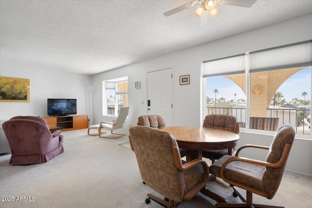 dining room featuring a textured ceiling, ceiling fan, and light carpet