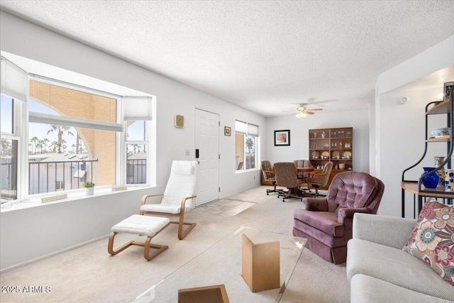 living room with ceiling fan, a textured ceiling, and light carpet