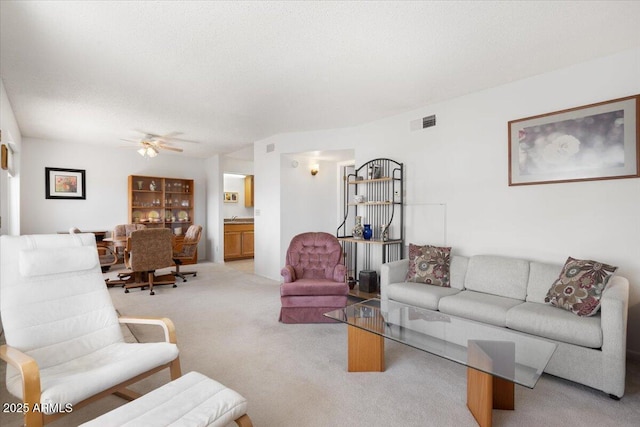 living room with light carpet, a textured ceiling, and ceiling fan