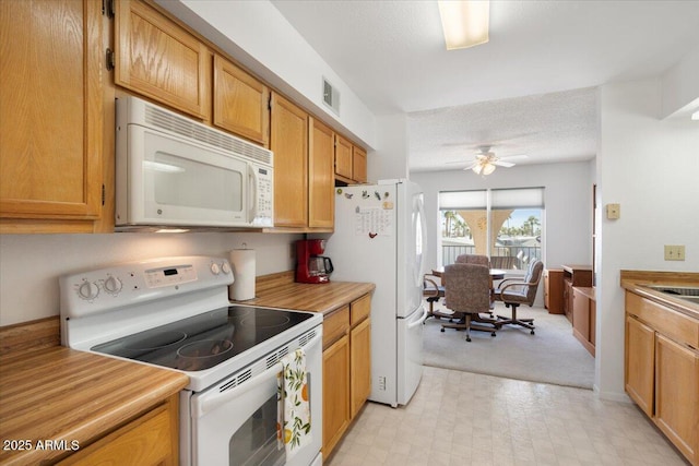 kitchen featuring a textured ceiling, white appliances, and ceiling fan