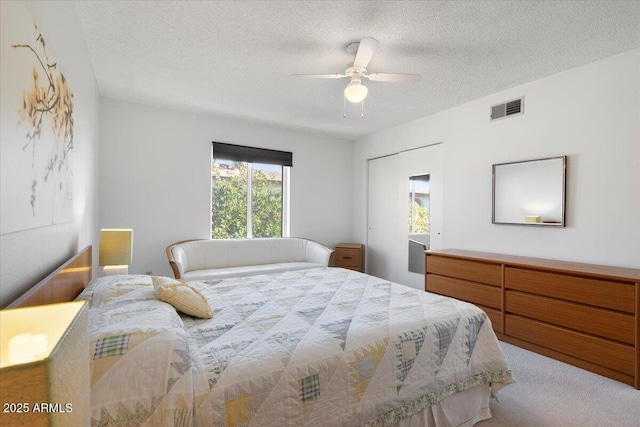 carpeted bedroom with ceiling fan and a textured ceiling