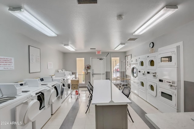 clothes washing area featuring a textured ceiling, washing machine and dryer, and stacked washer / drying machine