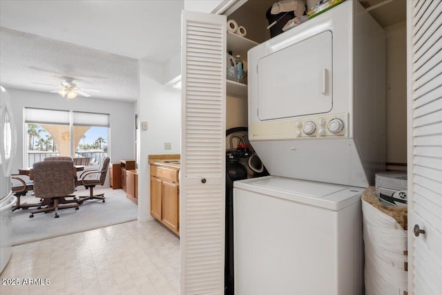 washroom featuring ceiling fan, stacked washing maching and dryer, and a textured ceiling