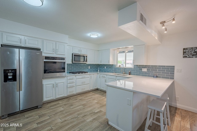 310 E Fremont Dr, Tempe, AZ 85282 - kitchen with stainless steel appliances, a sink, a peninsula, light wood-style floors, and white cabinetry