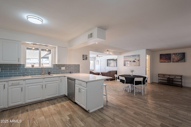 310 E Fremont Dr, Tempe, AZ 85282 - kitchen featuring a sink, stainless steel dishwasher, a peninsula, wood finished floors, and white cabinetry
