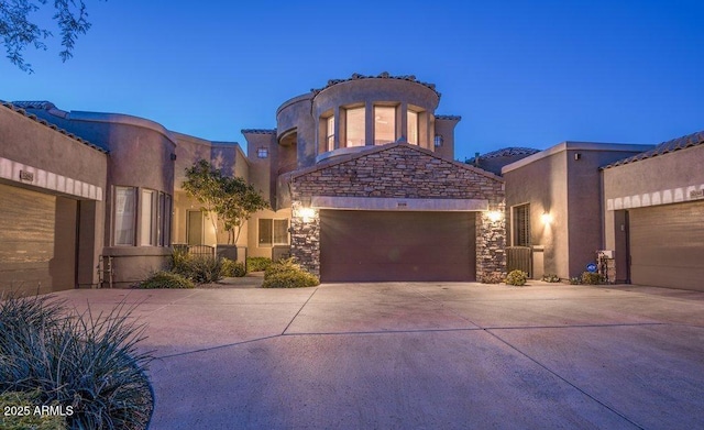 view of front of house featuring driveway, a garage, stucco siding, and stone siding
