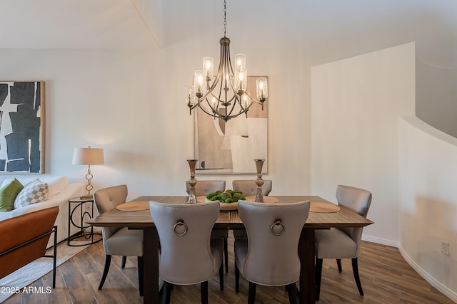 dining space featuring a chandelier, wood finished floors, and baseboards