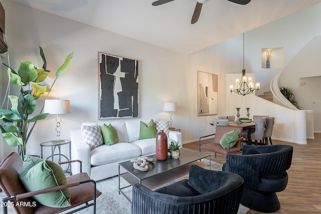 living room with wood finished floors, a chandelier, baseboards, ceiling fan, and vaulted ceiling