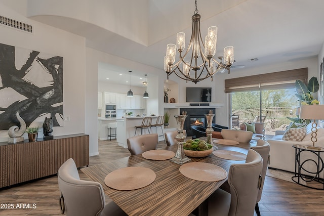 dining area featuring wood finished floors, a chandelier, and a glass covered fireplace