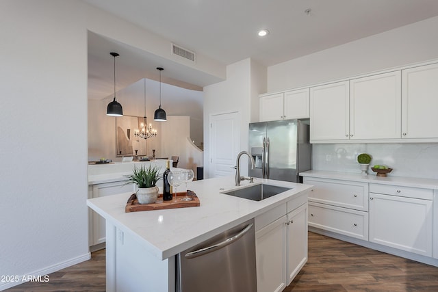 kitchen with appliances with stainless steel finishes, a sink, white cabinets, a kitchen island with sink, and dark wood-style flooring