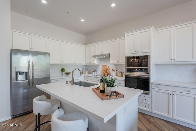 kitchen with black appliances, a sink, dark wood-style flooring, decorative backsplash, and recessed lighting