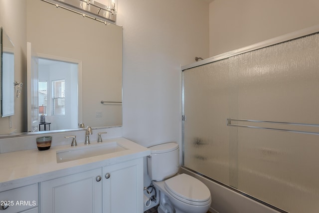bathroom featuring vanity, toilet, and combined bath / shower with glass door