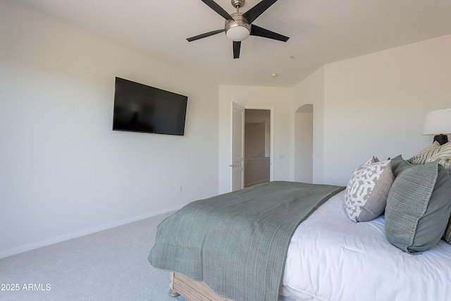 carpeted bedroom with arched walkways, baseboards, and ceiling fan