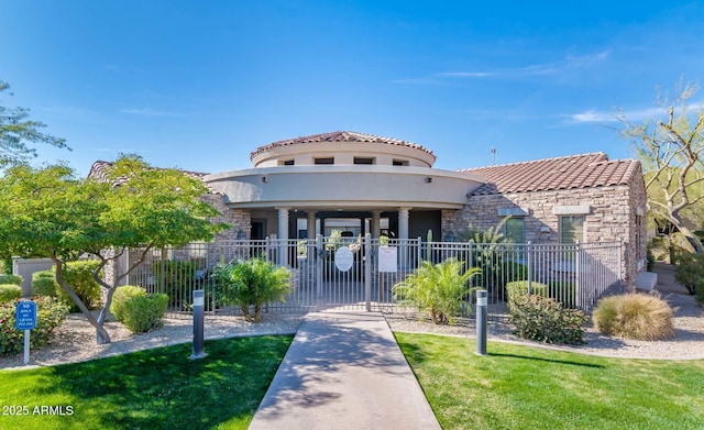 view of front of house with a fenced front yard, stucco siding, stone siding, a tiled roof, and a gate