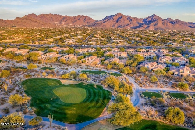 view of property location featuring a mountainous background, nearby suburban area, and a golf club