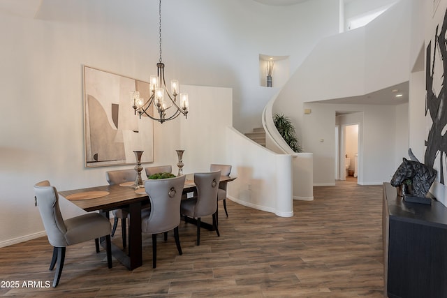 dining room featuring a high ceiling, wood finished floors, a chandelier, baseboards, and stairs