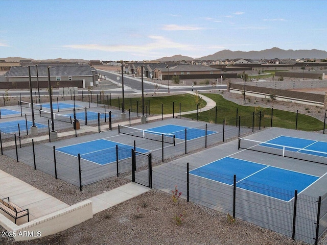 view of tennis court featuring a residential view, a mountain view, and fence