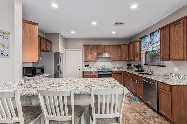 16077 W Anasazi St, Goodyear, AZ 85338 - kitchen with appliances with stainless steel finishes, under cabinet range hood, a peninsula, recessed lighting, and light stone counters