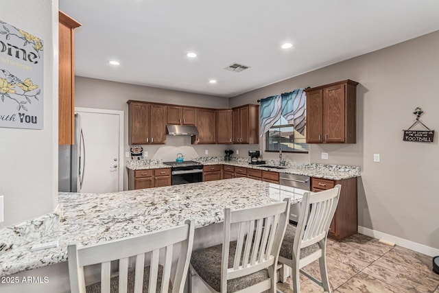 16077 W Anasazi St, Goodyear, AZ 85338 - kitchen with stainless steel appliances, under cabinet range hood, a peninsula, recessed lighting, and light stone countertops