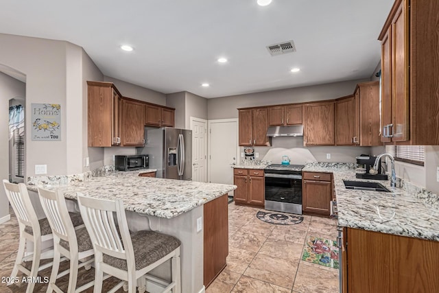 16077 W Anasazi St, Goodyear, AZ 85338 - kitchen with stainless steel appliances, under cabinet range hood, a peninsula, light stone countertops, and recessed lighting