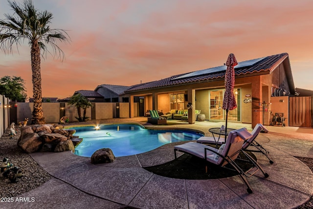 16077 W Anasazi St, Goodyear, AZ 85338 - pool at dusk with outdoor lounge area, a fenced backyard, and a patio area