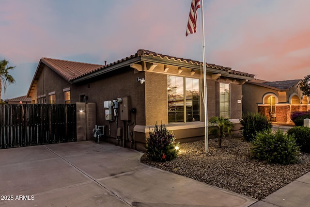 16077 W Anasazi St, Goodyear, AZ 85338 - property exterior at dusk with stucco siding, a gate, and a tiled roof