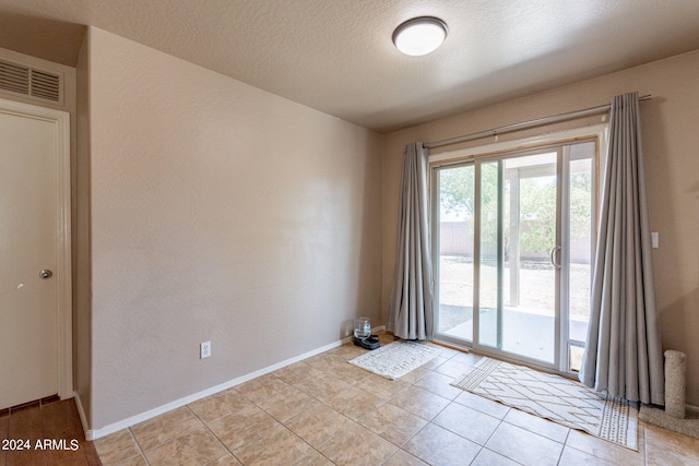 doorway featuring a textured ceiling and light tile patterned floors