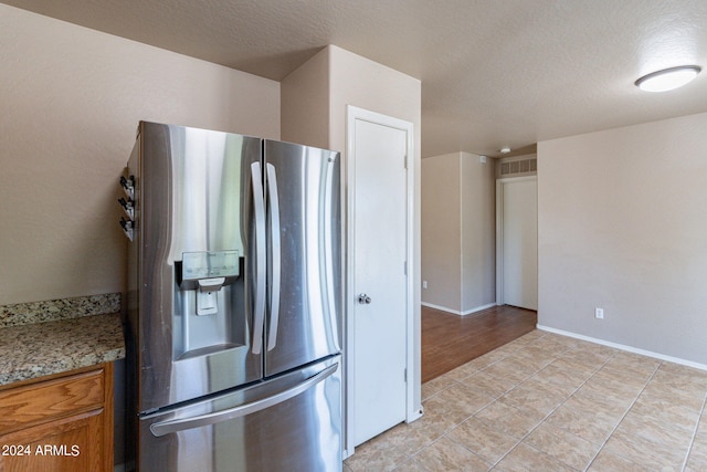 kitchen with a textured ceiling, stainless steel fridge with ice dispenser, and light hardwood / wood-style flooring