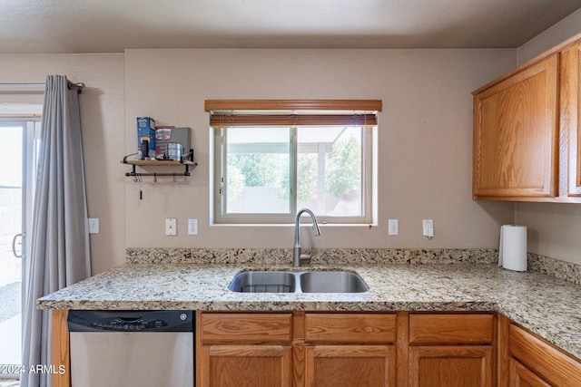 kitchen featuring dishwasher, light stone counters, a healthy amount of sunlight, and sink