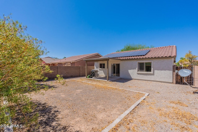 rear view of property featuring solar panels and a patio area