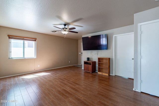 unfurnished living room featuring ceiling fan, dark wood-type flooring, and a textured ceiling