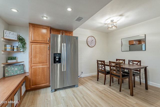 kitchen featuring light hardwood / wood-style flooring, stainless steel refrigerator with ice dispenser, brick wall, and fridge